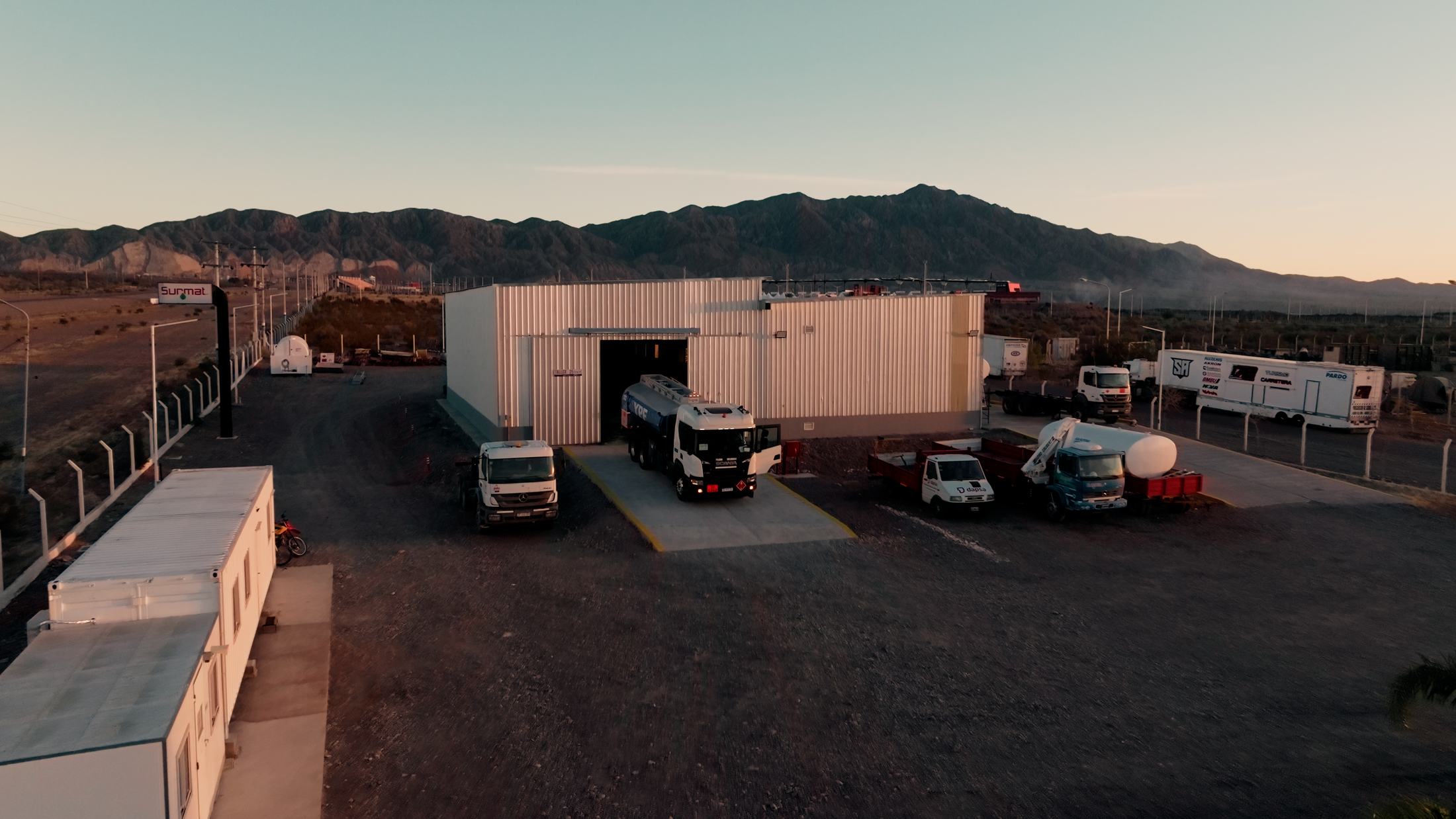 Vista aérea de la base y el taller de Surmat en el Parque Industrial Albardón, San Juan, con camiones cisterna y unidades de transporte al atardecer